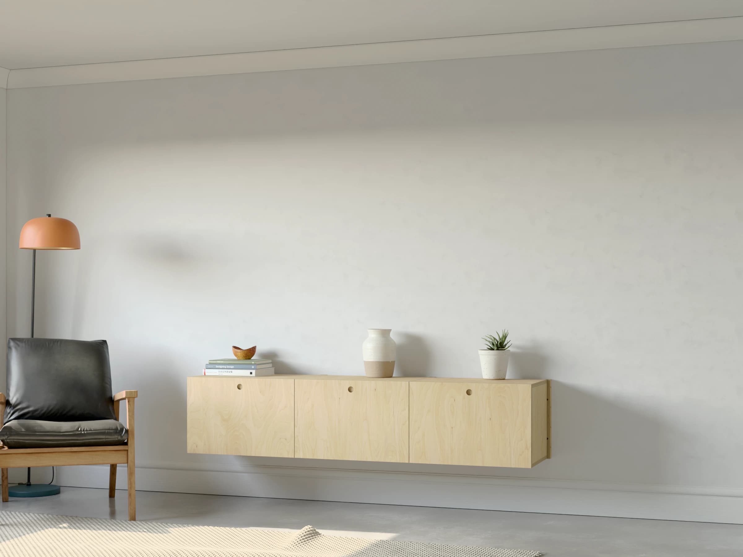 Three birch plywood drawer cabinets hung clear of the floor, with books, a vase and a plant on top, beside an armchair and a floor lamp