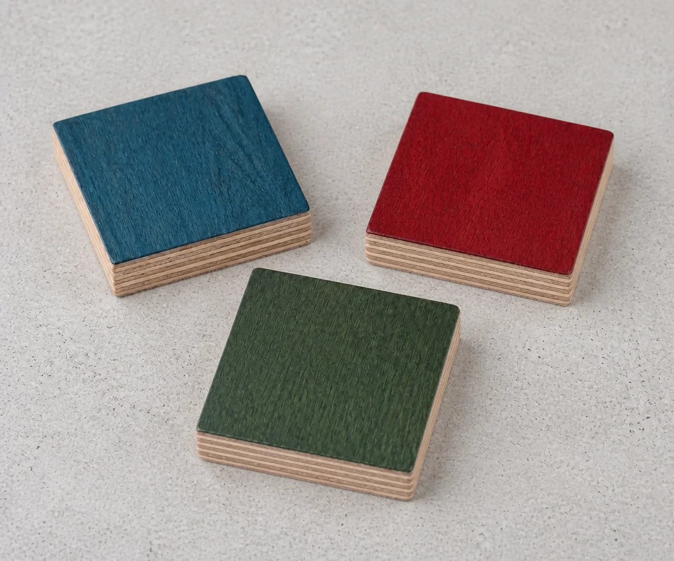 Blue, red, and green-stained plywood finish samples showing the layered edges