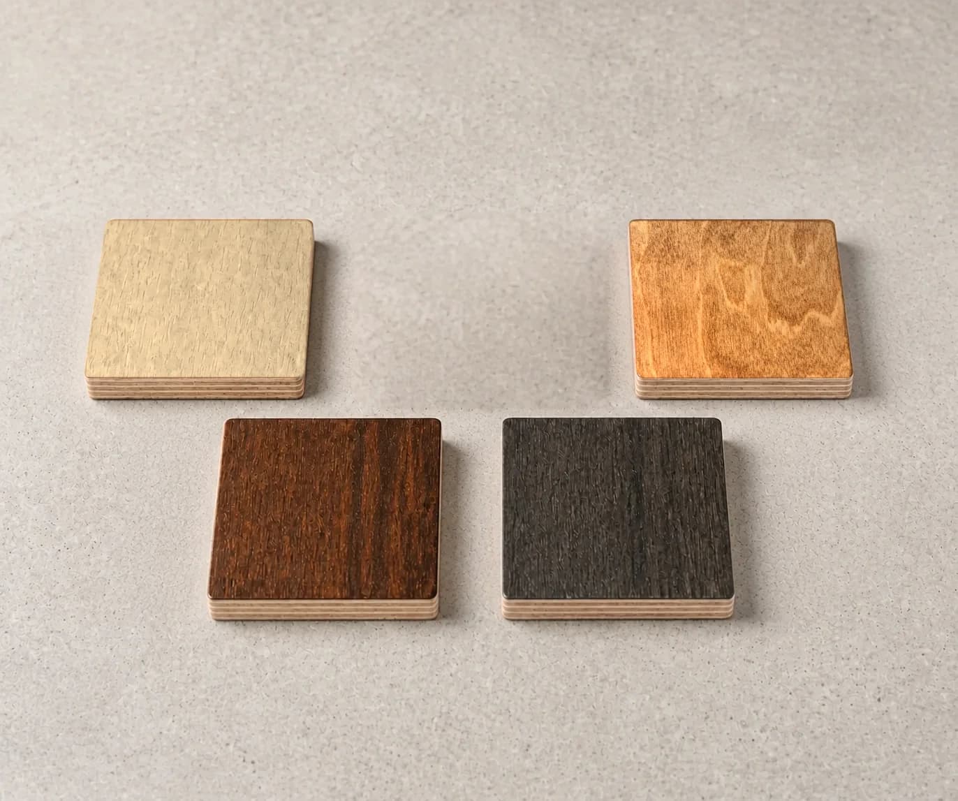 Four plywood finish samples in Natural, Hazelnut, Cocoa, and Charcoal, showing the layered edges